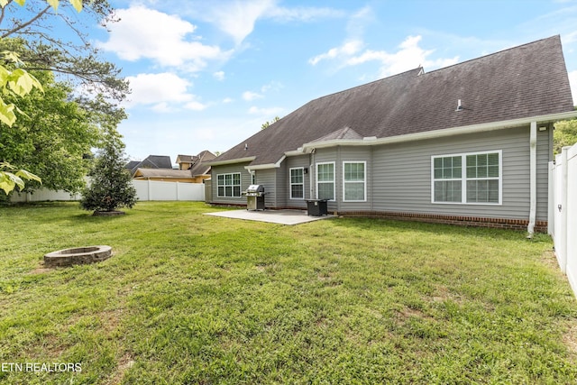 back of property featuring roof with shingles, a fenced backyard, a yard, a patio, and a fire pit