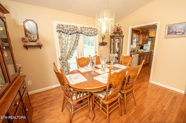 dining space featuring baseboards, an inviting chandelier, light wood-style flooring, and vaulted ceiling