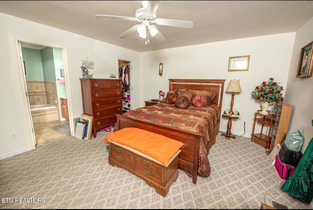 bedroom with a textured ceiling, ceiling fan, connected bathroom, and a spacious closet
