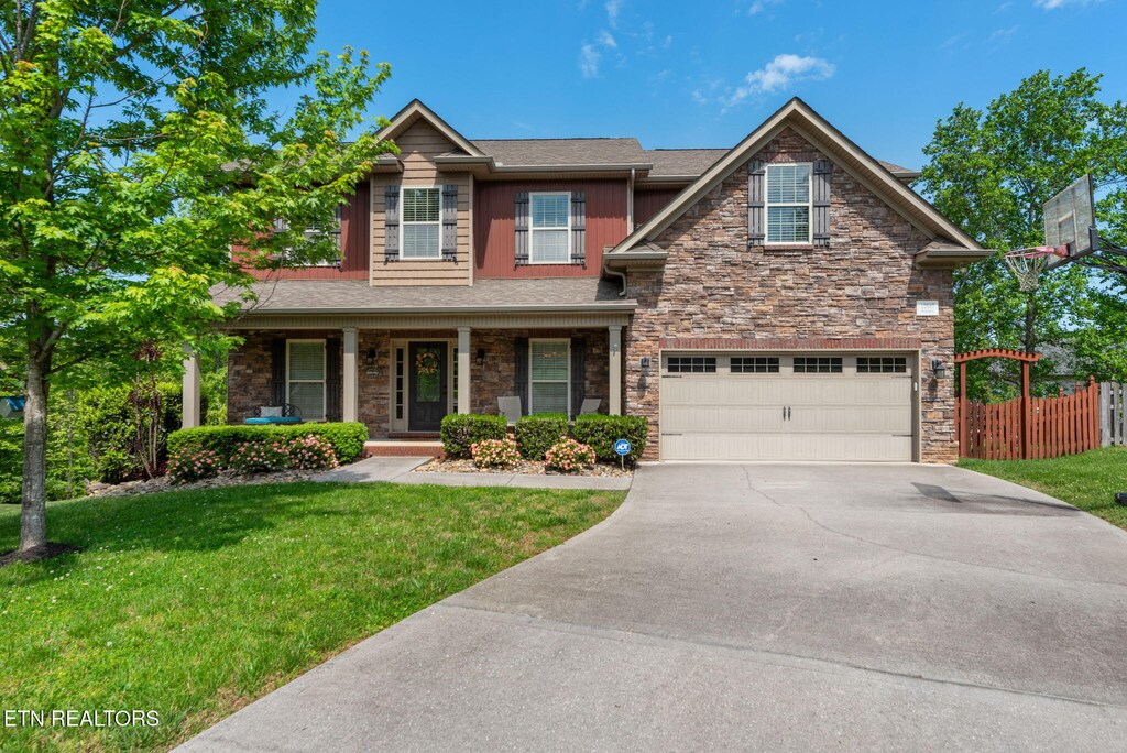 12947 Pine Meadows Ln, Knoxville, TN 37934 - craftsman-style house featuring fence, a front lawn, stone siding, a garage, and driveway