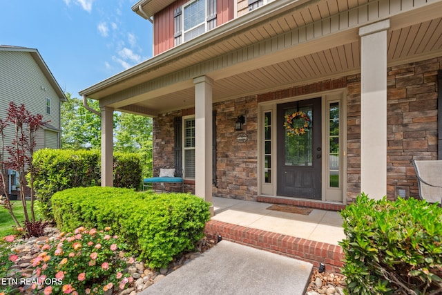property entrance with board and batten siding, a porch, and stone siding