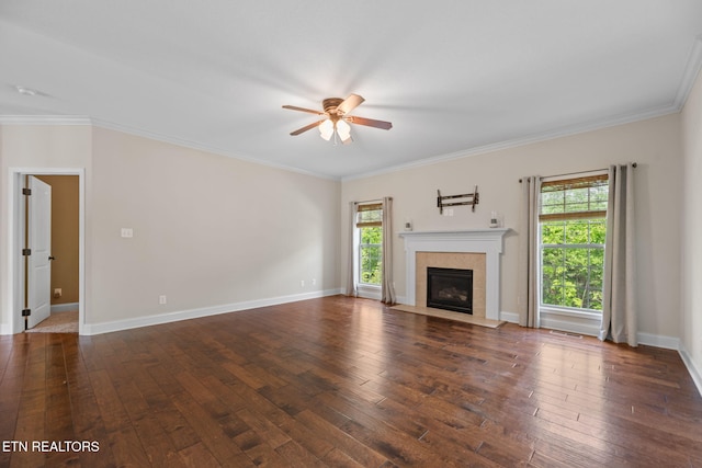 unfurnished living room featuring crown molding, baseboards, dark wood-type flooring, a tile fireplace, and a ceiling fan