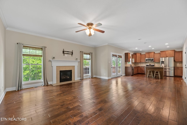 unfurnished living room featuring a ceiling fan, a fireplace with flush hearth, crown molding, dark wood finished floors, and baseboards