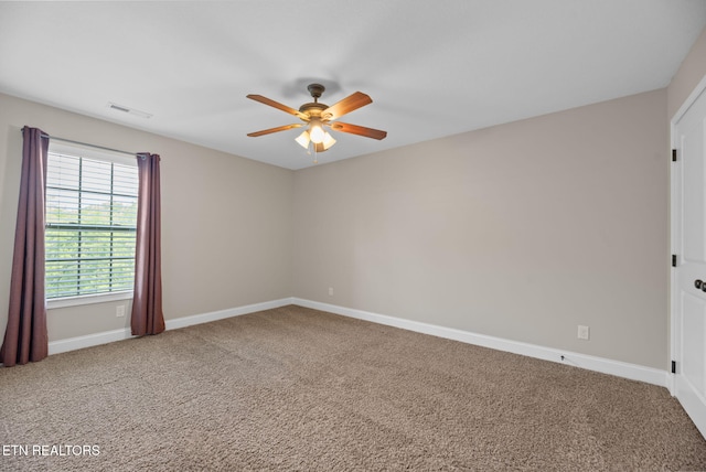 carpeted empty room with baseboards, a ceiling fan, and visible vents