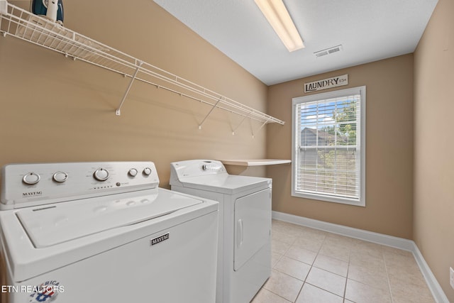laundry area with light tile patterned flooring, laundry area, baseboards, visible vents, and washing machine and dryer