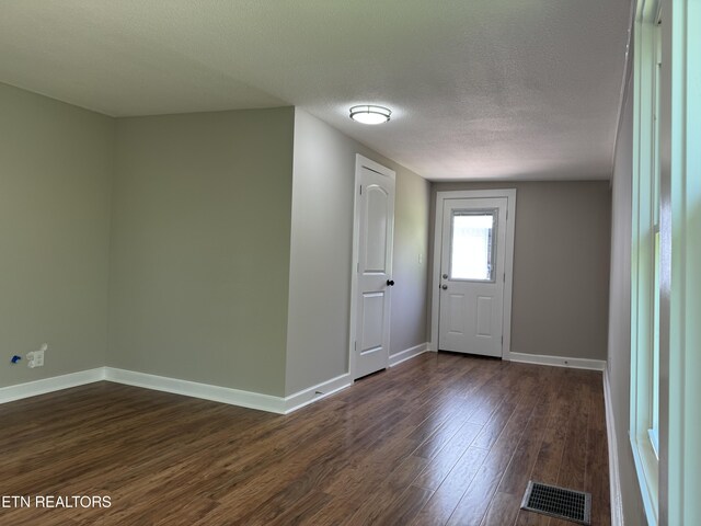 entryway with baseboards, visible vents, a textured ceiling, and dark wood-style flooring