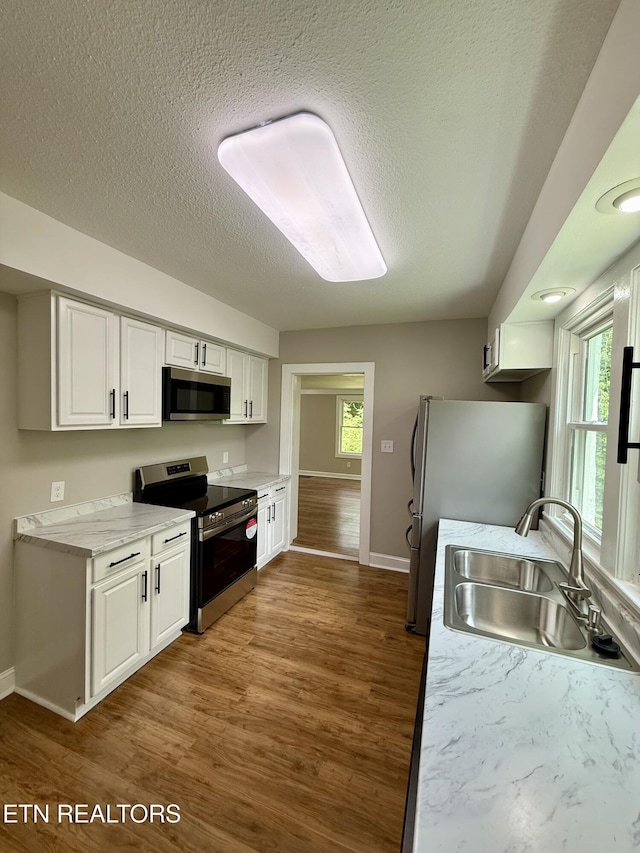 kitchen with a wealth of natural light, stainless steel appliances, baseboards, and a sink