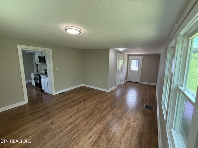 foyer entrance with baseboards, visible vents, a textured ceiling, and dark wood-style flooring