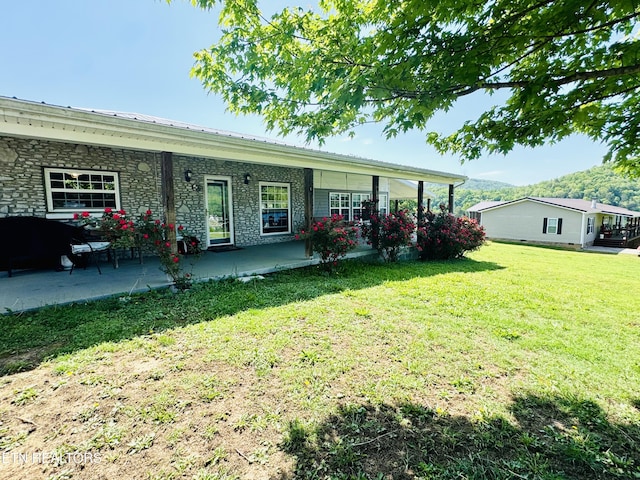 back of property with a lawn, a patio area, and metal roof