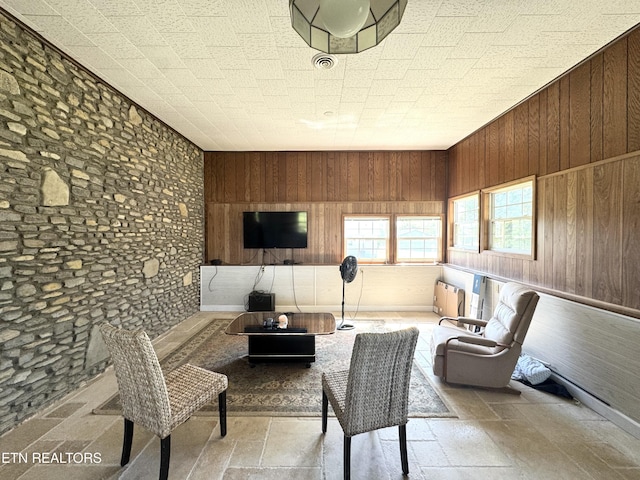 living room with wood walls and stone tile floors
