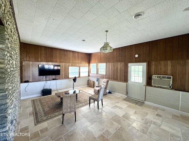 interior space featuring wooden walls, stone tile floors, visible vents, and a wall unit AC