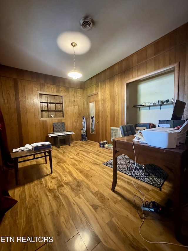 office area featuring wood walls, visible vents, and light wood-type flooring
