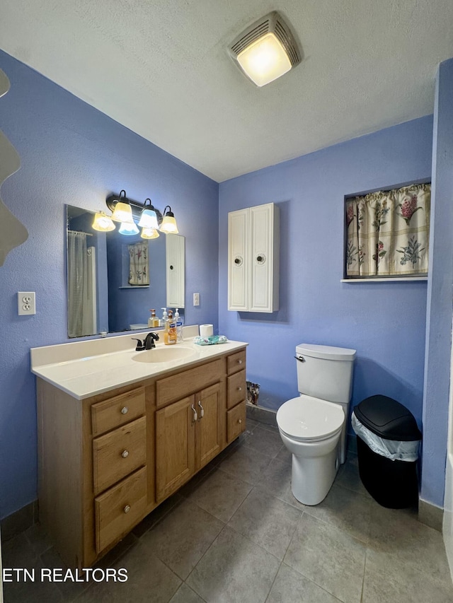 full bath with a textured ceiling, baseboards, tile patterned floors, vanity, and toilet