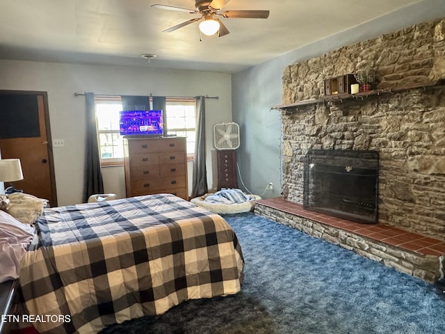 carpeted bedroom featuring ceiling fan and a fireplace
