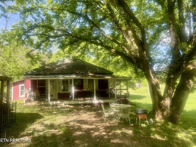 rear view of property featuring a porch and a lawn
