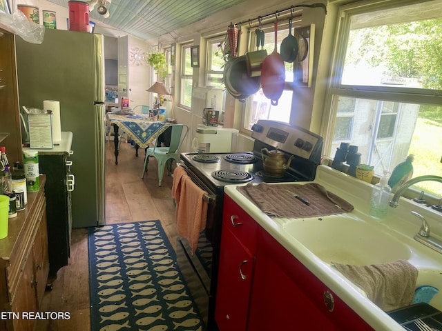 kitchen with wooden ceiling, freestanding refrigerator, electric range, red cabinetry, and light wood-type flooring