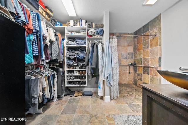 spacious closet featuring stone tile floors
