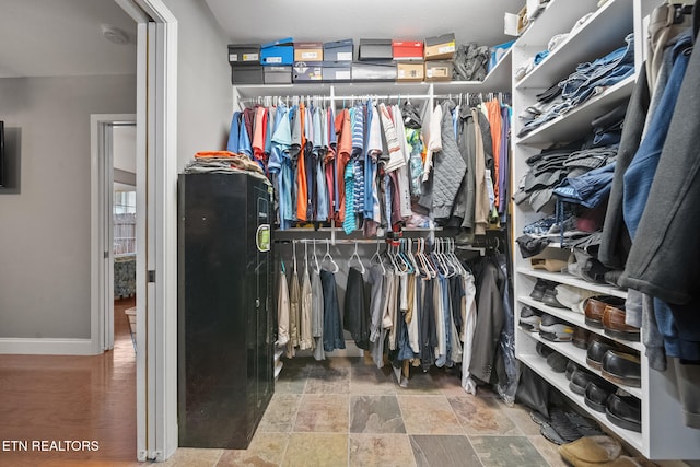 spacious closet featuring stone finish floor