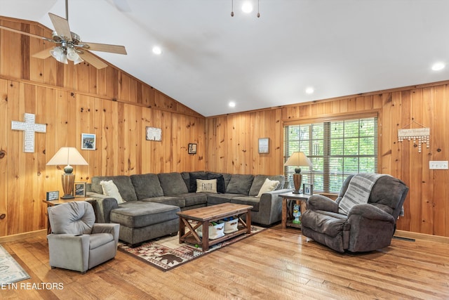 living room featuring wooden walls, ceiling fan, lofted ceiling, and hardwood / wood-style floors