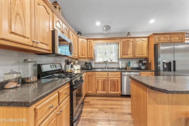 kitchen with dark stone countertops, recessed lighting, a sink, light wood-style flooring, and stainless steel appliances