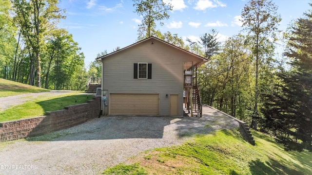 view of side of home featuring a garage, stairs, and gravel driveway
