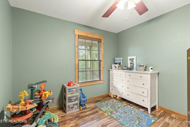 game room with a ceiling fan, baseboards, and wood finished floors