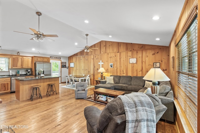 living area featuring a ceiling fan, wood walls, lofted ceiling, recessed lighting, and light wood-style flooring
