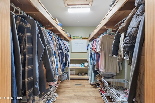 spacious closet featuring visible vents, wood finished floors, and attic access