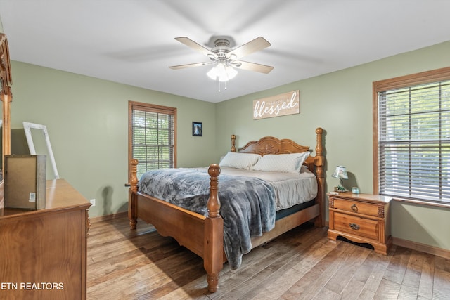 bedroom with light wood-type flooring, baseboards, and ceiling fan