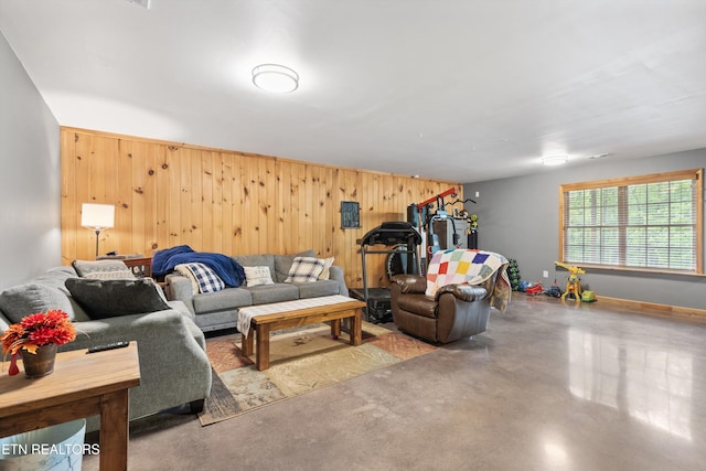 living area featuring baseboards, concrete floors, and wooden walls