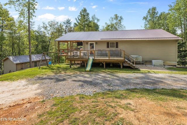 back of property with a wooden deck, metal roof, and stairway