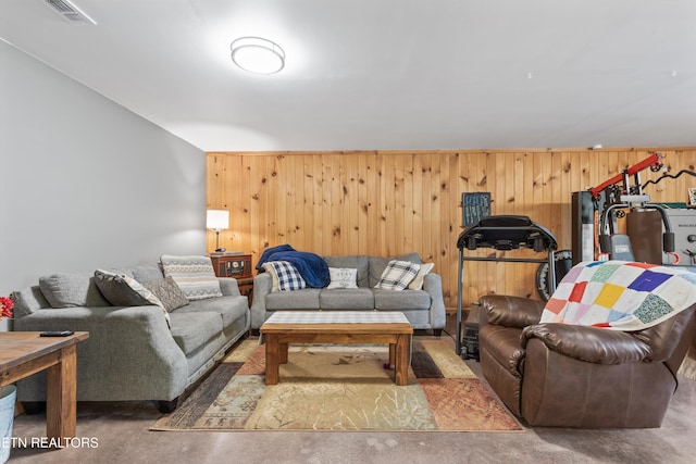 living room featuring visible vents, finished concrete flooring, and wooden walls