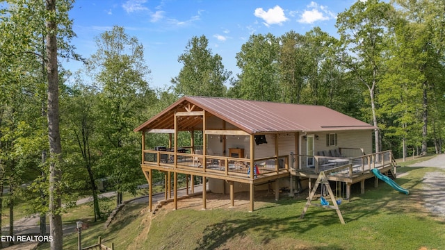 rear view of house with a lawn, a wooden deck, and metal roof