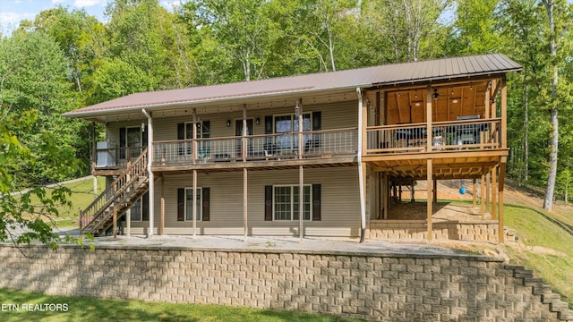 rear view of property with a deck, metal roof, stairway, and a patio
