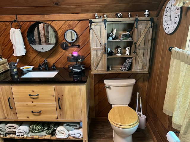 bathroom with wood finished floors, wooden walls, toilet, and vanity