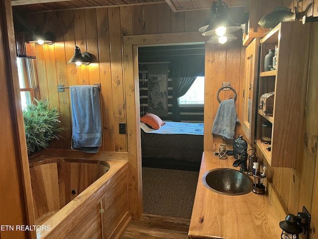 bathroom featuring wood walls, wood finished floors, ensuite bathroom, and a bath