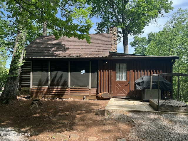 view of front of house with a sunroom, board and batten siding, and a chimney