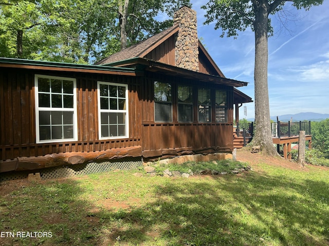 view of home's exterior with a lawn, a chimney, board and batten siding, and a mountain view