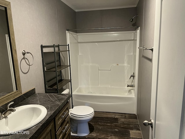 full bathroom featuring wood finished floors, shower / bathing tub combination, toilet, a textured wall, and vanity