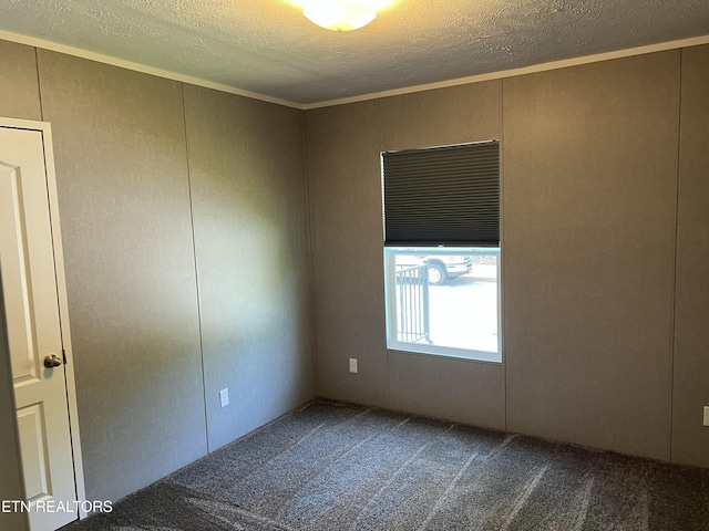 unfurnished room with dark colored carpet, a textured ceiling, a decorative wall, and crown molding
