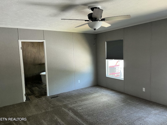 unfurnished room featuring a textured ceiling, carpet flooring, visible vents, a decorative wall, and a ceiling fan