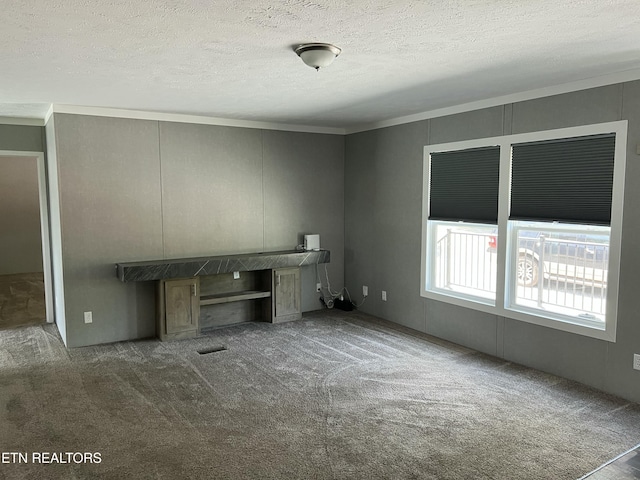 unfurnished living room with ornamental molding, a textured ceiling, a decorative wall, and carpet