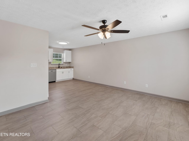 unfurnished living room with a sink, a textured ceiling, a ceiling fan, baseboards, and visible vents