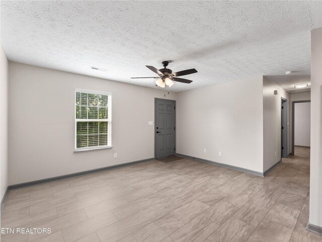 spare room with visible vents, a textured ceiling, baseboards, and ceiling fan
