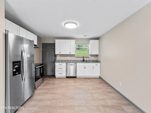 kitchen with white cabinets, light stone countertops, appliances with stainless steel finishes, a sink, and under cabinet range hood