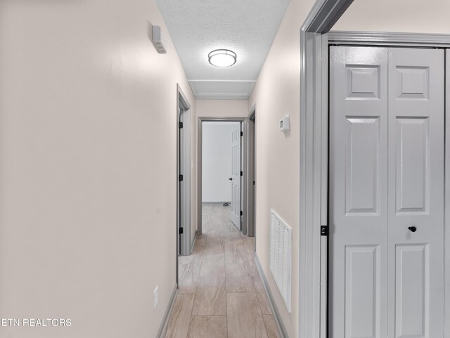 hall featuring visible vents, a textured ceiling, and marble finish floor