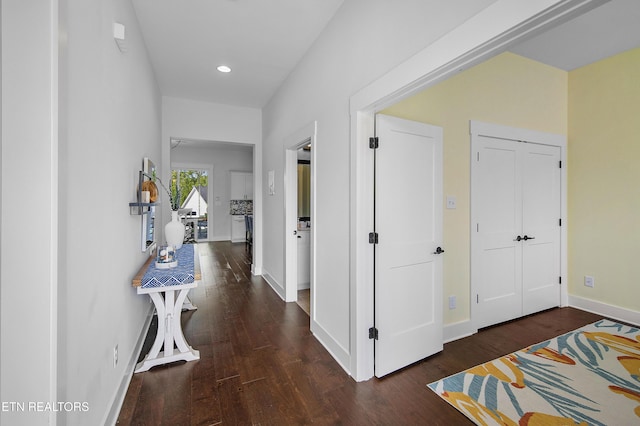 hallway featuring dark wood-type flooring, recessed lighting, and baseboards