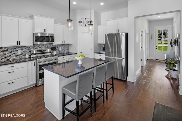kitchen with a breakfast bar area, tasteful backsplash, appliances with stainless steel finishes, and white cabinetry