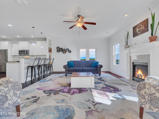 living area with crown molding, recessed lighting, ceiling fan, and a high end fireplace