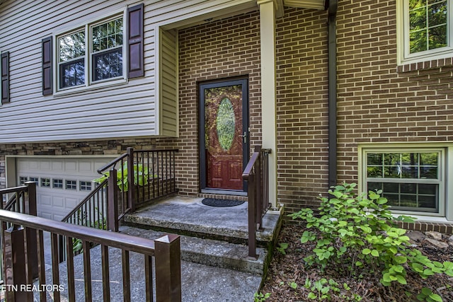 view of exterior entry featuring brick siding and an attached garage
